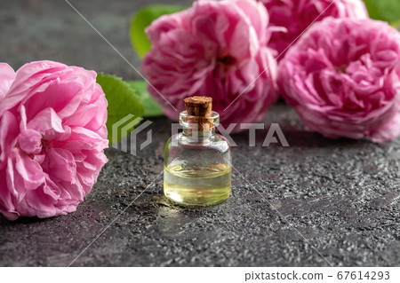 A bottle of rose essential oil with rose flowers 67614293
