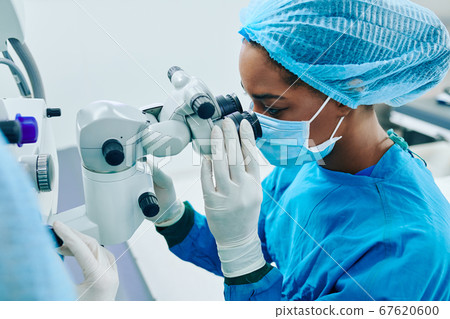 Surgeon looking through electronic miscroscope Surgeon looking through electronic miscroscope 67620600