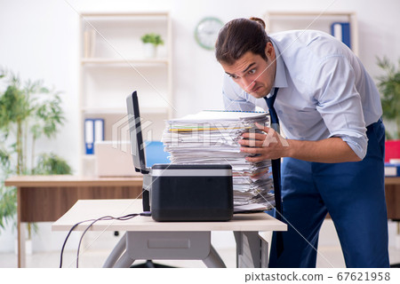 Young male employee making copies at copying machine Young male employee making copies at copying machine 67621958