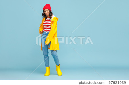 Happy ethnic woman in a yellow raincoat smiling on 67621989
