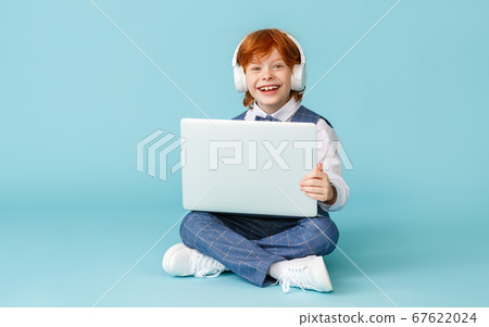 Happy schoolboy smiling and using laptop. 67622024