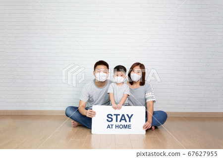 Asian family wearing protective medical mask holding white paper with stay at home. Asian family wearing protective medical mask holding white paper with stay at home. 67627955