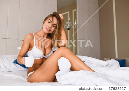 Woman with morning drink cup in bed Woman with morning drink cup in bed 67628217