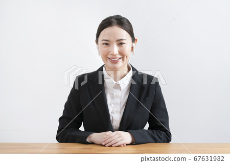 A young woman in a suit wearing wireless headphones looking at the camera A young woman in a suit wearing wireless headphones looking at the camera 67631982