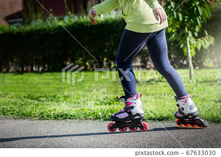 Teenage girl is skating on roller blades in the 67633030