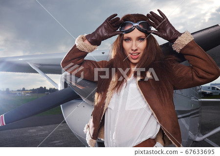 A young female pilot is standing next to a small A young female pilot is standing next to a small 67633695