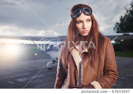 A young female pilot is standing next to a small A young female pilot is standing next to a small 67633697