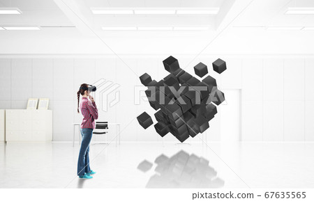 Girl in virtual reality mask experiencing virtual technology world. Mixed media 67635565