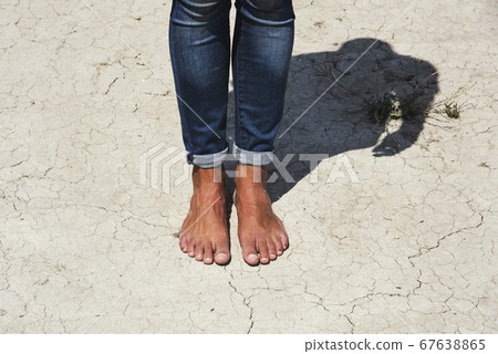 bare feet of a man on a cracked dry soil 67638865