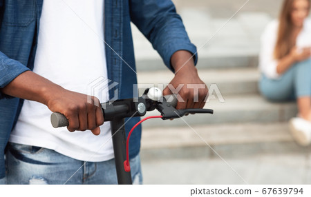 Black man holding handle of a stand-up scooter Black man holding handle of a stand-up scooter 67639794