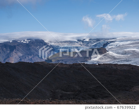 View over a landscape of Godland and thorsmork with the Eyjafjallajokull glacier and volcano, lava formations, snow, ice and green moss. Iceland, Fimmvorduhals hiking trail. Summer cloudy day. 67639922