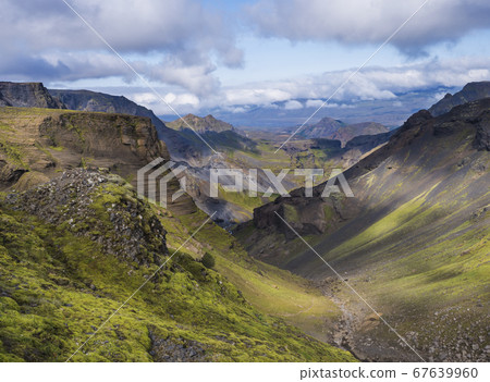 Landscape of Godland and thorsmork with rugged green moss covered rocks and hills, bending river canyon, Iceland, Fimmvorduhals hiking trail. Summer blue sky white clouds 67639960