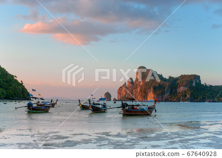 Charming sunset over a tropical island. Low tide, fishing boats. 67640928