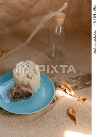 Luffa sponge on a ceramic blue trowel. Background sand and craft paper. 67640960