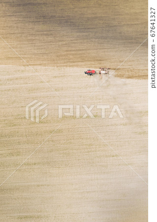 Aerial View. Tractor With Seed Drill Machine Sowing The Seeds For Crops In Spring Season. Beginning Of Agricultural Spring Season. Countryside Field Landscape. Natural Rural Background Aerial View. Tractor With Seed Drill Machine Sowing The Seeds For Crops In Spring Season. Beginning Of Agricultural Spring Season. Countryside Field Landscape. Natural Rural Background 67641327