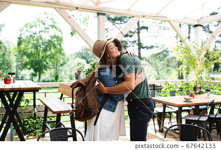 Happy couple greeting outdoors on terrace restaurant, hugging. Happy couple greeting outdoors on terrace restaurant, hugging. 67642133