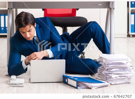 Tired exhausted businessman working overtime in office Tired exhausted businessman working overtime in office 67642707