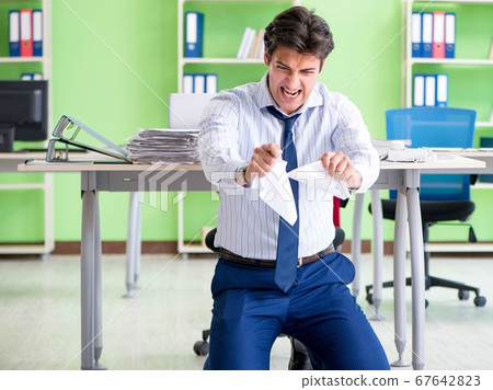 Frustrated businessman stressed from excessive work Frustrated businessman stressed from excessive work 67642823