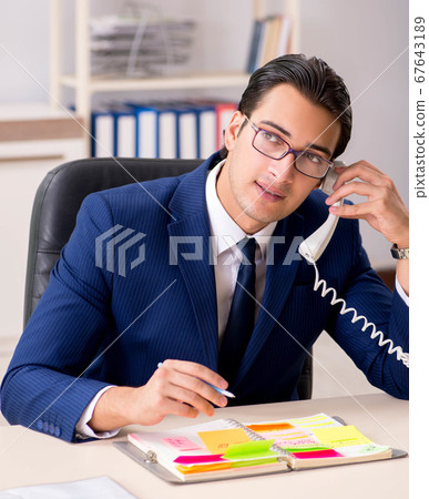 Young handsome employee planning his work activity Young handsome employee planning his work activity 67643189