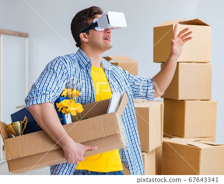 Young man wearing VR glasses moving in new apartment 67643341