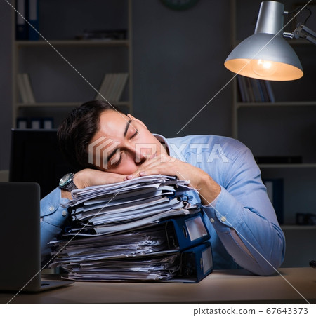Employee working late at night at important report Employee working late at night at important report 67643373