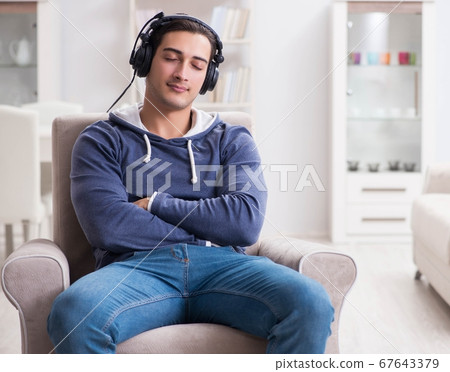 Young man listening to music at home Young man listening to music at home 67643379