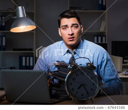 Young employee working overtime to meet deadline Young employee working overtime to meet deadline 67643386