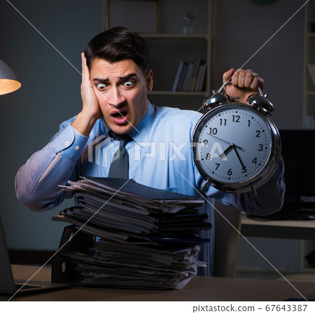 Young employee working overtime to meet deadline Young employee working overtime to meet deadline 67643387