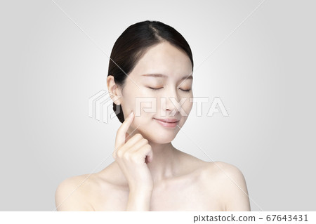 Young woman touching her face with a relaxed expression Young woman touching her face with a relaxed expression 67643431