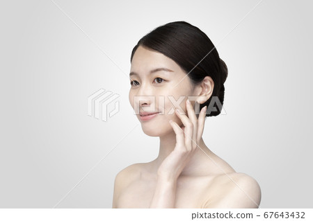 Young woman touching her face with a relaxed expression Young woman touching her face with a relaxed expression 67643432