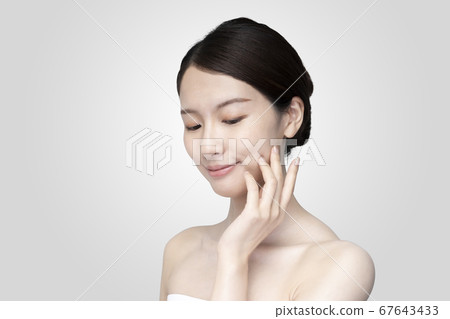 Young woman touching her face with a relaxed expression Young woman touching her face with a relaxed expression 67643433