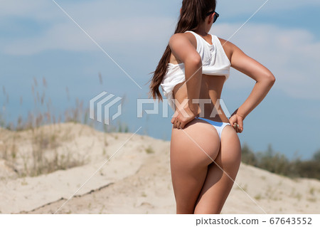 Crop woman with firm buttocks on beach Crop woman with firm buttocks on beach 67643552
