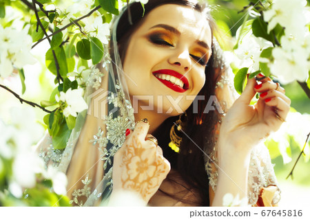 young pretty indian girl in jewelry and veil posing cheerful happy smiling in green park, lifestyle people concept young pretty indian girl in jewelry and veil posing cheerful happy smiling in green park, lifestyle people concept 67645816