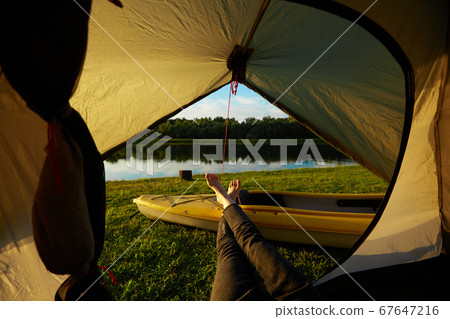 Feet of young women relaxing with lake view from tent camping entrance outdoor. Travel wanderlust lifestyle concept adventure vacations outdoor, Summer holiday and vacation trip 67647216