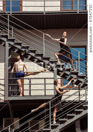 The group of modern ballet dancers performing on the stairs at the city The group of modern ballet dancers performing on the stairs at the city 67647592