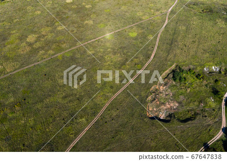 The view from the top, like a dirt unpaved roads cross the meadow. Shot on drone.  67647838