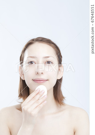 Woman doing base makeup 67648551