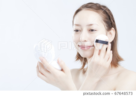 Woman doing base makeup Woman doing base makeup 67648573