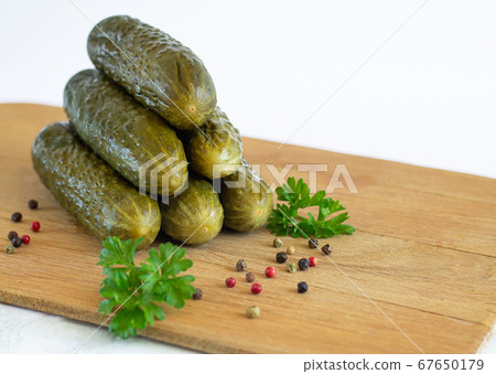 Pickled or fermented organic cucumbers with parsley and spice on wood board isolated on white background 67650179