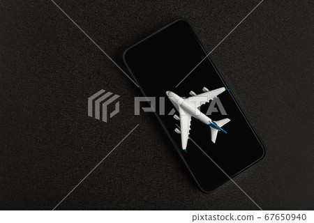 Model airplane on smartphone on black background. 67650940