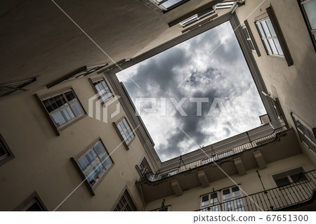 Narrow Courtyard With View Up To The Cloudy Sky Of A Historic Building Narrow Courtyard With View Up To The Cloudy Sky Of A Historic Building 67651300