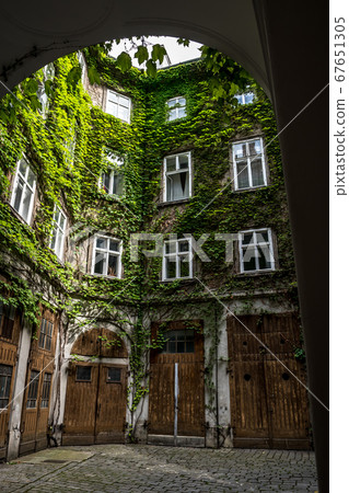 Courtyard Of A HIstoric Building With Wooden Doors And Ivy Overgrown Walls 67651305