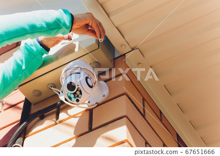 technician female setup cctv camera on wall. 67651666