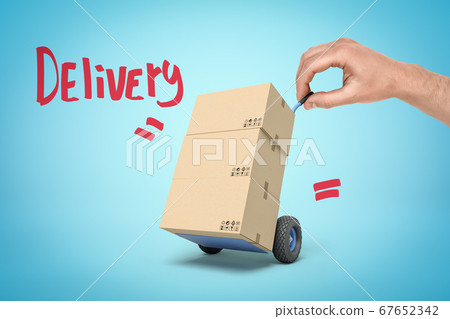 Hand holding tiny hand truck with cardboard boxes and 'Delivery' sign on blue background Hand holding tiny hand truck with cardboard boxes and 'Delivery' sign on blue background 67652342