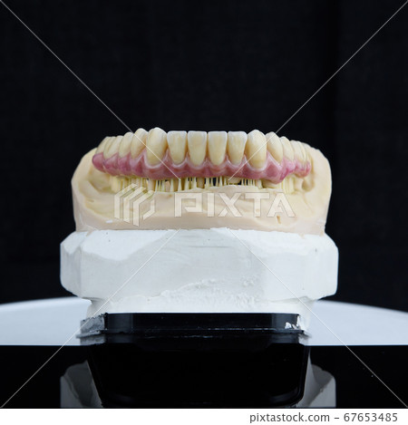 Dental technician working with articulator in dental lab 67653485
