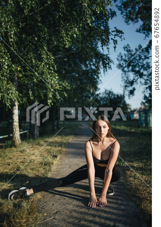 Runner doing stretching exercise before workout Runner doing stretching exercise before workout 67654892