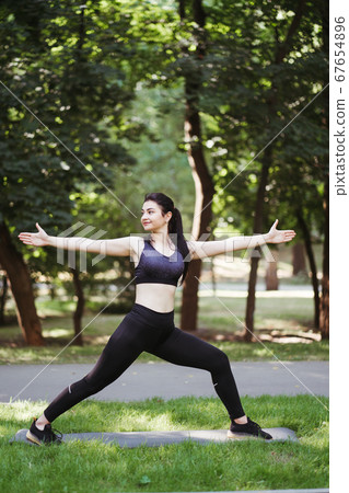 Fit woman doing yoga exercises in the park. Fit woman doing yoga exercises in the park. 67654896