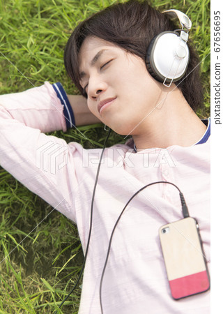 A man listening to music lying on the grass 67656695