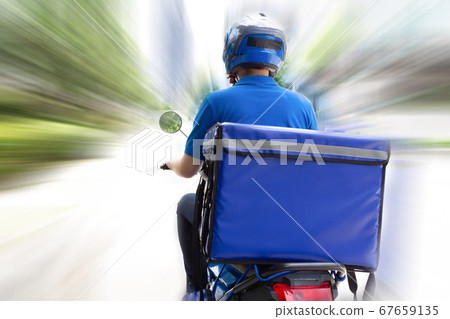 Delivery man wearing blue uniform riding motorcycle and delivery box. Delivery man wearing blue uniform riding motorcycle and delivery box. 67659135