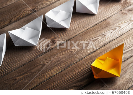 Business leadership concept with white and color paper boats on wooden table Business leadership concept with white and color paper boats on wooden table 67660408